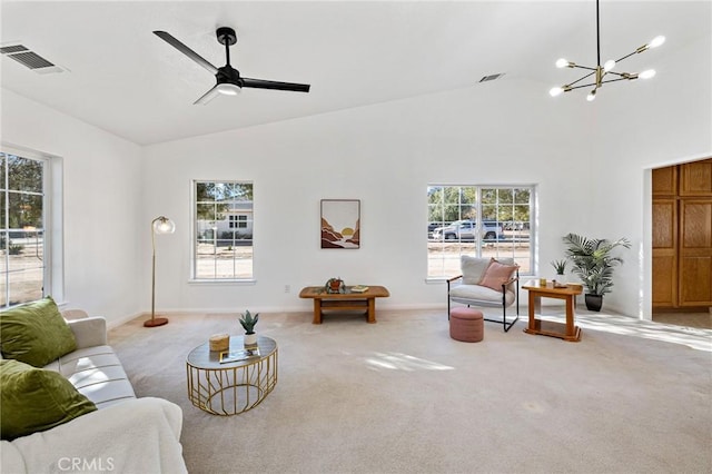 living room with high vaulted ceiling, ceiling fan with notable chandelier, and light colored carpet