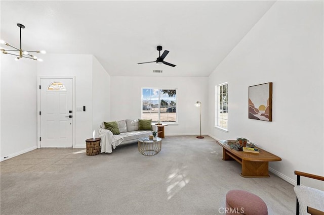 living room featuring ceiling fan with notable chandelier, vaulted ceiling, and light colored carpet