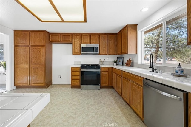 kitchen with sink, tile counters, and appliances with stainless steel finishes