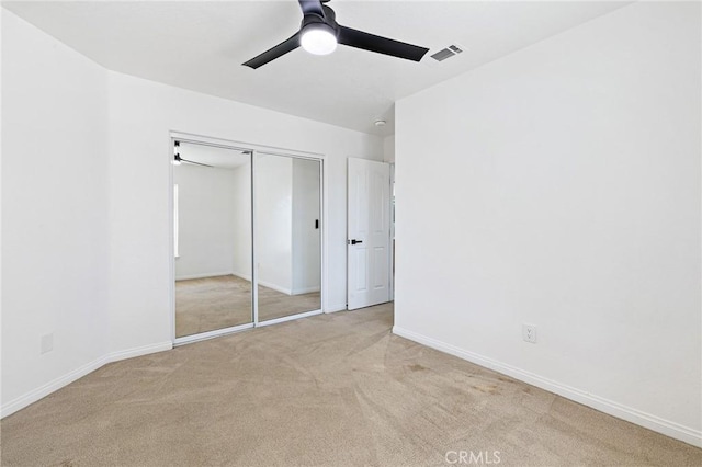 unfurnished bedroom featuring light colored carpet, a closet, and ceiling fan