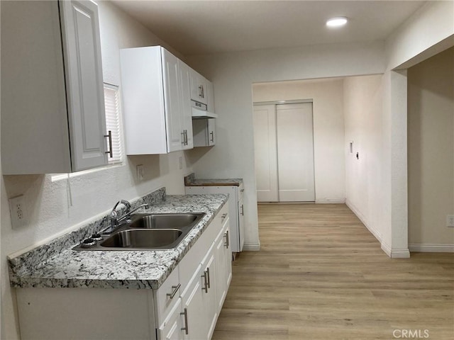 21483 Main St, Barstow, CA 92311 - kitchen with sink, white cabinetry, range, light stone countertops, and light hardwood / wood-style floors