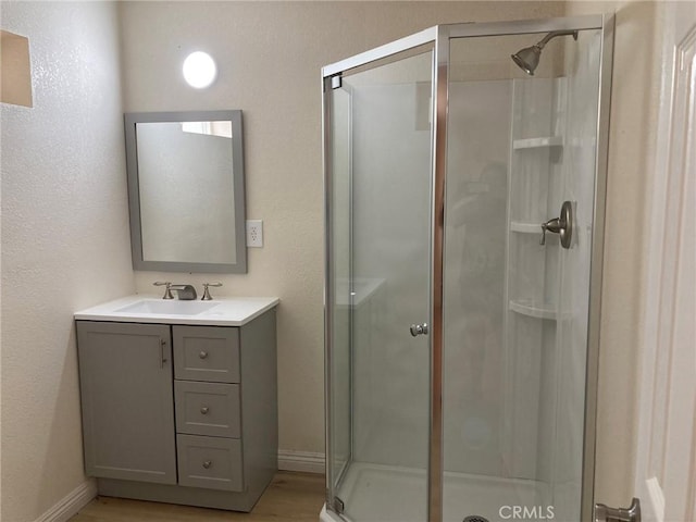 21483 Main St, Barstow, CA 92311 - bathroom featuring a shower with door, vanity, and hardwood / wood-style flooring
