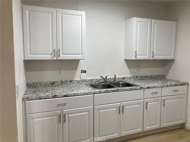 21483 Main St, Barstow, CA 92311 - kitchen featuring white cabinetry, light hardwood / wood-style floors, sink, and light stone countertops