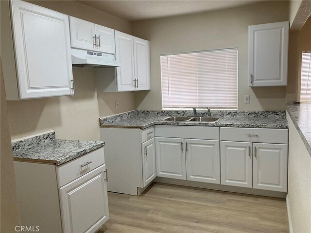 21483 Main St, Barstow, CA 92311 - kitchen featuring white cabinetry, light stone countertops, sink, and light hardwood / wood-style flooring