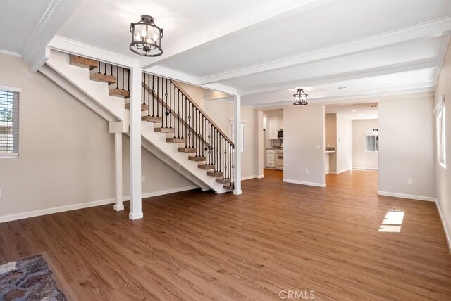 unfurnished living room featuring beamed ceiling, ornamental molding, dark hardwood / wood-style floors, and a notable chandelier