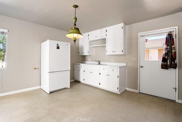 kitchen with white cabinetry, hanging light fixtures, sink, and white refrigerator