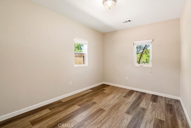 empty room with hardwood / wood-style flooring and a healthy amount of sunlight