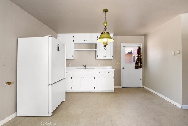 kitchen with hanging light fixtures, white fridge, sink, and white cabinets