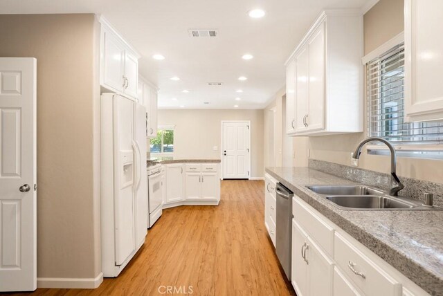 kitchen with white cabinetry, white appliances, sink, and light hardwood / wood-style flooring