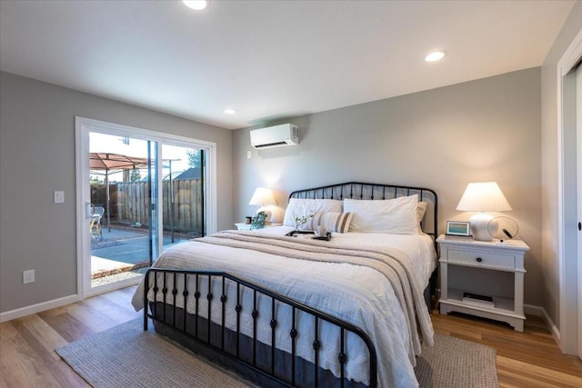 bedroom featuring a wall mounted air conditioner, access to exterior, and light wood-type flooring