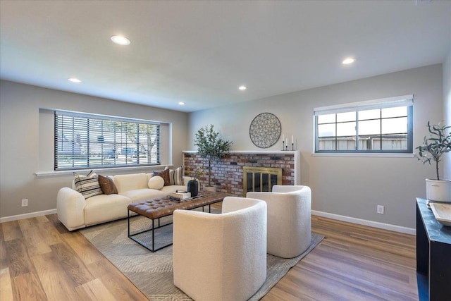 living room with a brick fireplace and hardwood / wood-style flooring