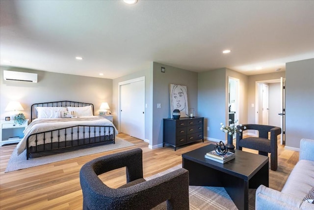 bedroom with a wall mounted air conditioner and light hardwood / wood-style floors