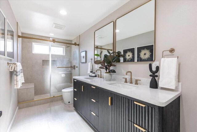 bathroom featuring vanity, toilet, and a shower with shower door