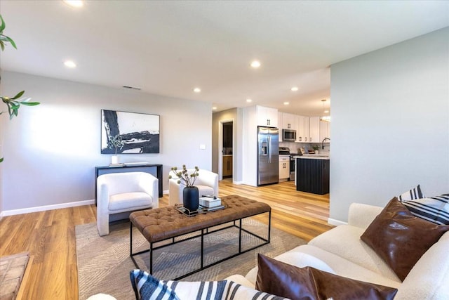 living room with sink and light hardwood / wood-style flooring