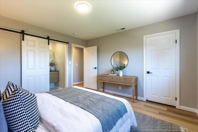 bedroom with a barn door and light wood-type flooring