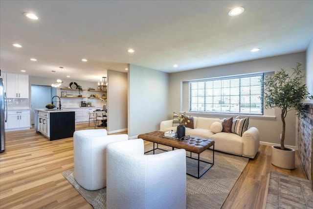 living room featuring sink and light hardwood / wood-style flooring