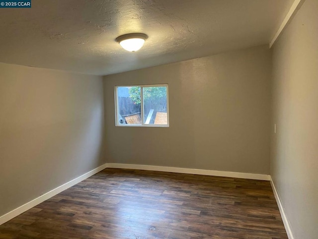 spare room featuring dark wood-type flooring and a textured ceiling