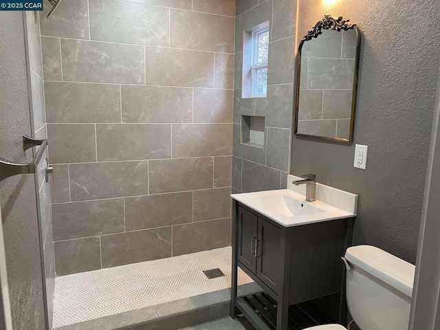 bathroom with vanity, toilet, and a tile shower