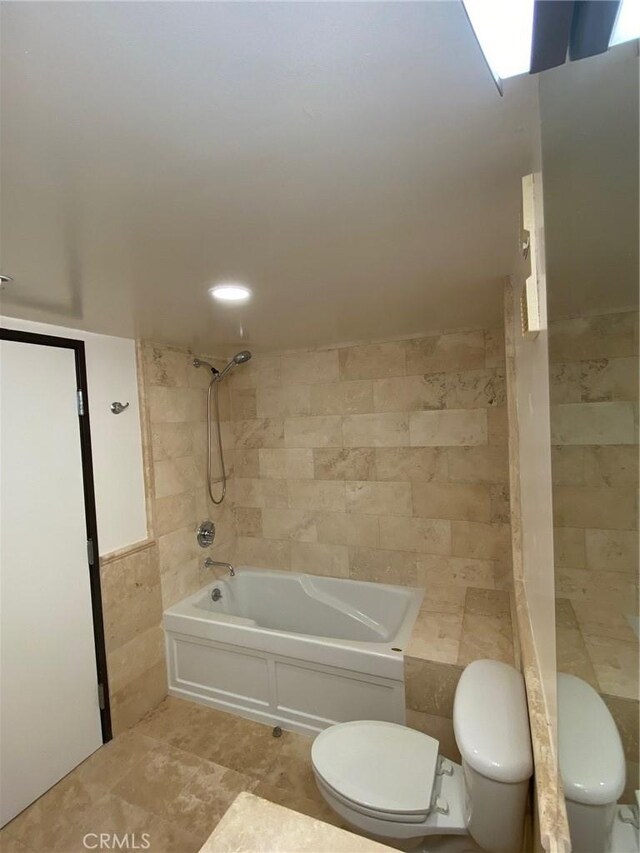 bathroom featuring tile walls, tiled shower / bath, and toilet