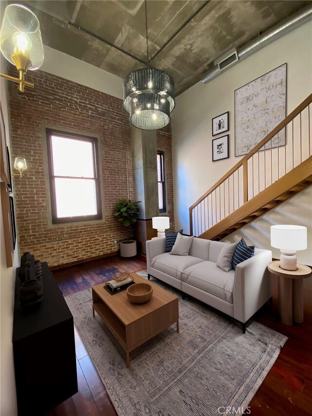 living room featuring brick wall and dark wood-type flooring