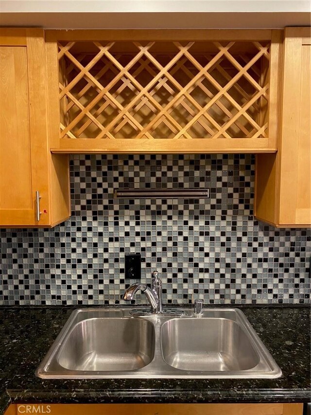 kitchen with dark stone counters, sink, and decorative backsplash