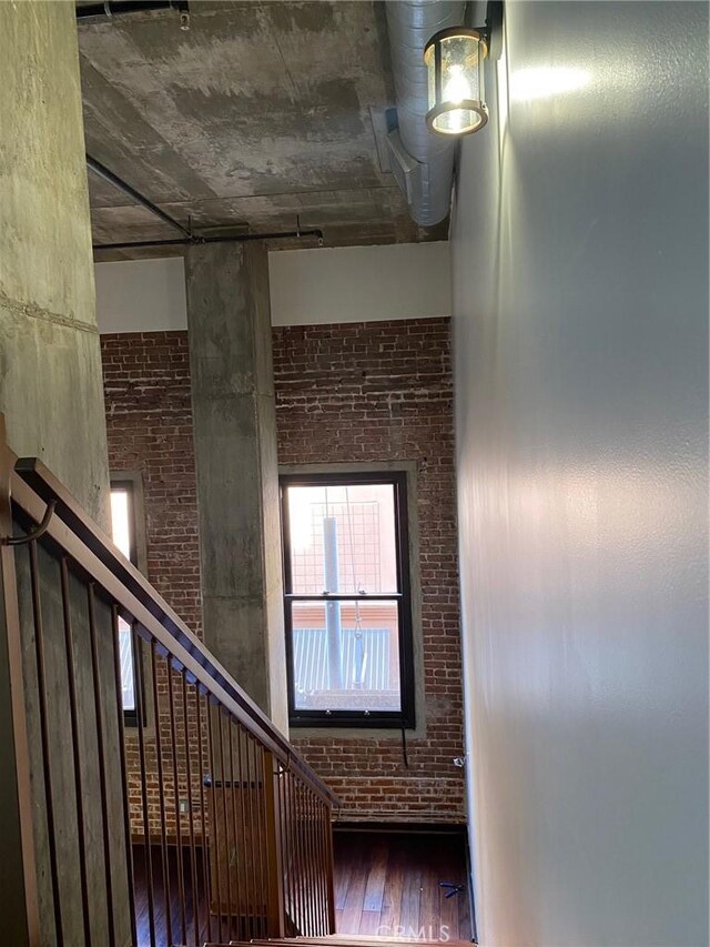 stairway with hardwood / wood-style flooring and brick wall