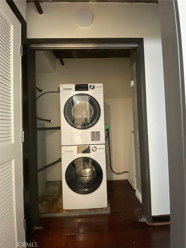 laundry room featuring dark hardwood / wood-style floors and stacked washing maching and dryer