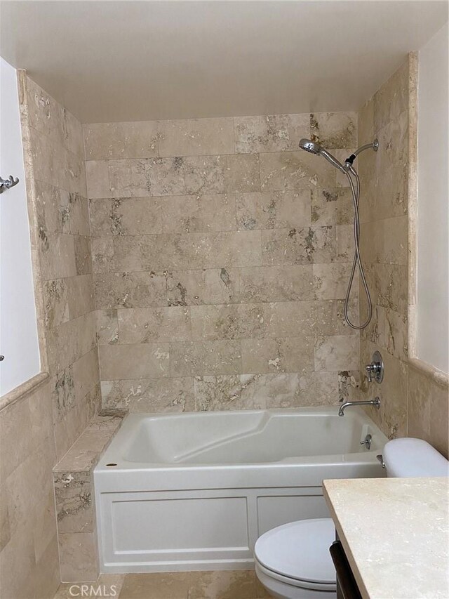 full bathroom featuring vanity, toilet, tiled shower / bath combo, and tile walls