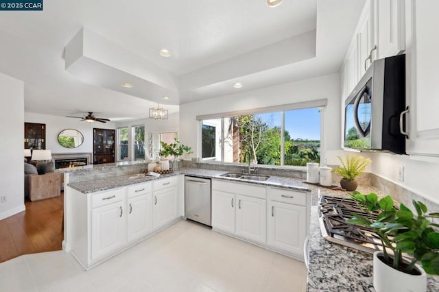 kitchen with light stone counters, stainless steel appliances, sink, and white cabinets