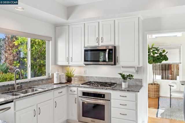 kitchen featuring light stone counters, sink, white cabinets, and appliances with stainless steel finishes