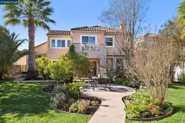 rear view of house featuring a balcony, a yard, and a patio area