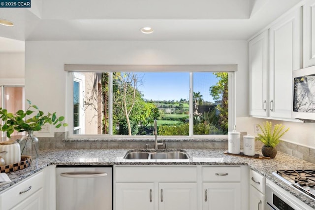 kitchen with light stone countertops, appliances with stainless steel finishes, sink, and white cabinets