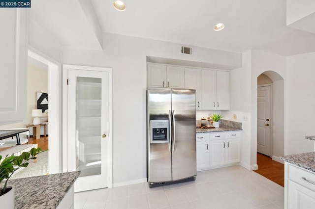 kitchen featuring stainless steel refrigerator with ice dispenser, white cabinetry, and light stone counters