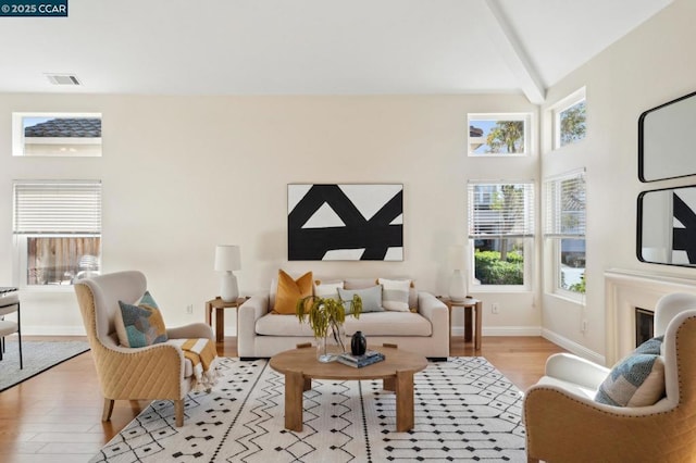 living room featuring beam ceiling, high vaulted ceiling, and light hardwood / wood-style flooring