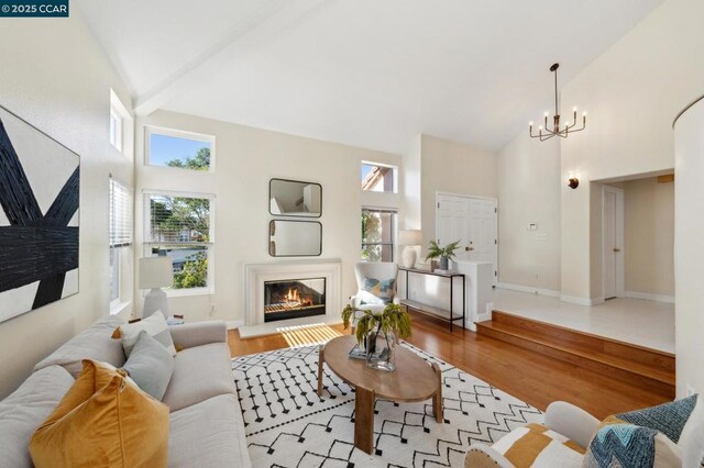 living room featuring beam ceiling, high vaulted ceiling, and light wood-type flooring