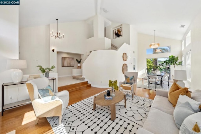 living room with a chandelier, high vaulted ceiling, and light hardwood / wood-style flooring