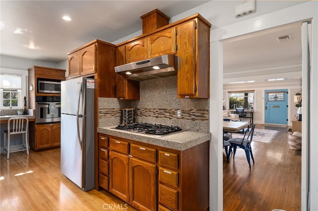 kitchen featuring stainless steel appliances, light hardwood / wood-style floors, and decorative backsplash