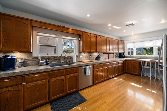 kitchen featuring sink, backsplash, light hardwood / wood-style flooring, and appliances with stainless steel finishes