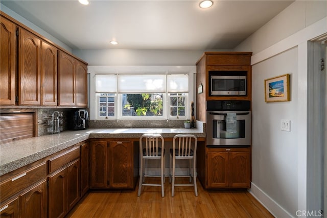 kitchen featuring stainless steel appliances, light hardwood / wood-style floors, and decorative backsplash