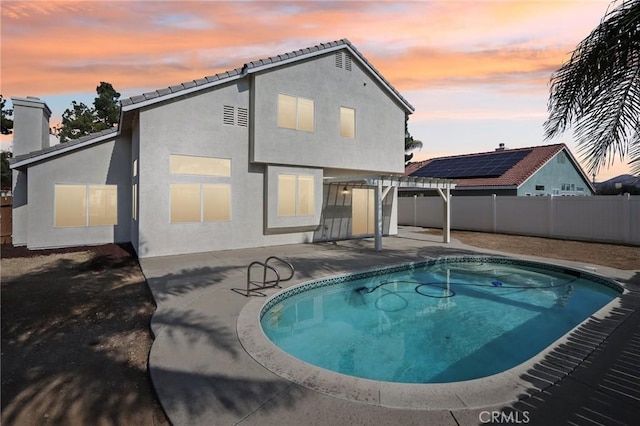 back house at dusk with a fenced in pool, a pergola, and a patio area