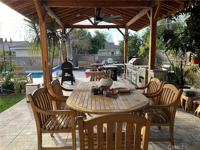 view of patio / terrace with ceiling fan, a fenced in pool, a gazebo, and exterior kitchen