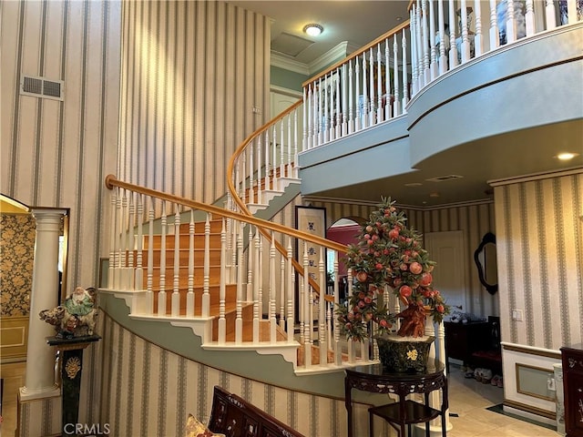 stairway with ornamental molding, a high ceiling, and ornate columns