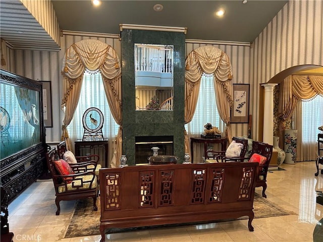 living area featuring a fireplace, ornate columns, and plenty of natural light