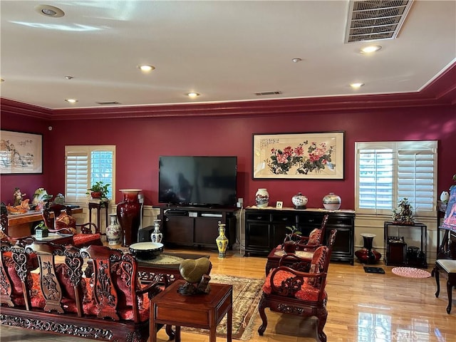 living room with light wood-type flooring, a wealth of natural light, and ornamental molding