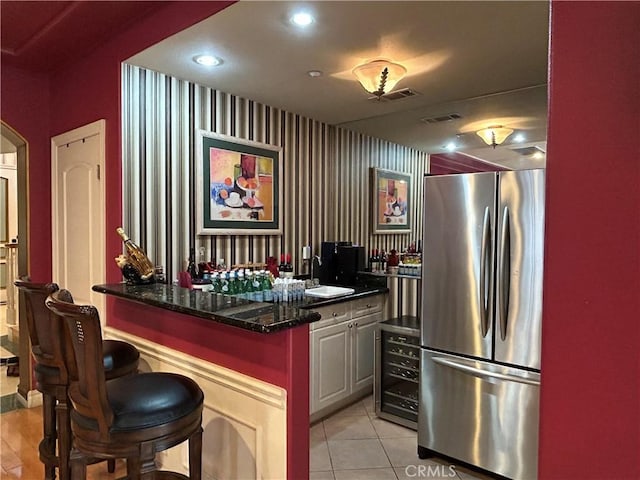 kitchen with stainless steel refrigerator, sink, a kitchen bar, dark stone countertops, and wine cooler