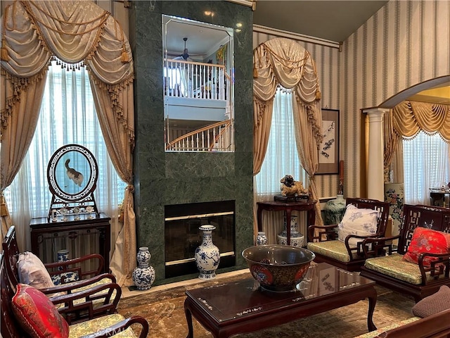 sitting room featuring ceiling fan, a premium fireplace, and ornate columns