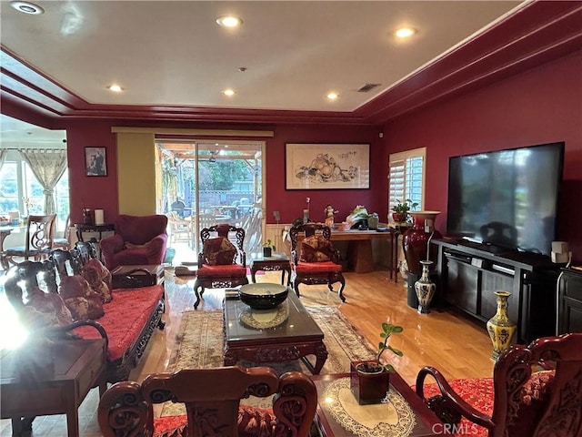 living room featuring a tray ceiling, light wood-type flooring, and crown molding