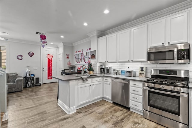 kitchen with sink, white cabinetry, tasteful backsplash, appliances with stainless steel finishes, and kitchen peninsula