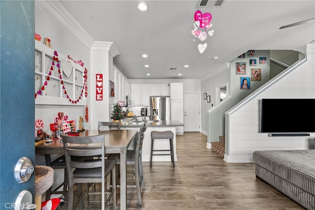 kitchen with crown molding, white cabinetry, a kitchen breakfast bar, stainless steel refrigerator with ice dispenser, and wood-type flooring