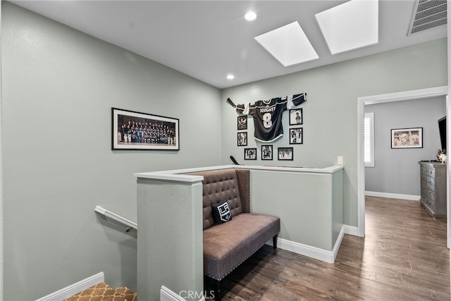 sitting room with dark wood-type flooring and a skylight